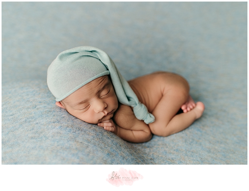 Newborn baby boy on tummy with blue hat