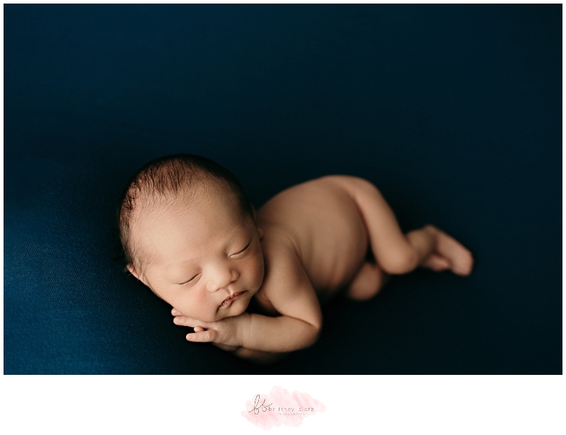 Baby boy side laying on blue jewel tone fabric
