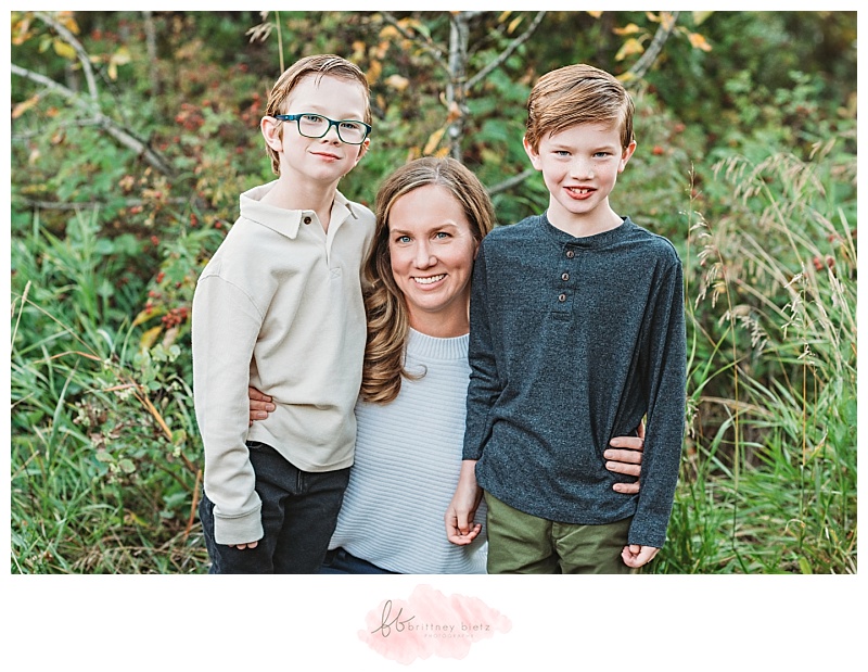 Mom kneeling down and smiling with her two young sons