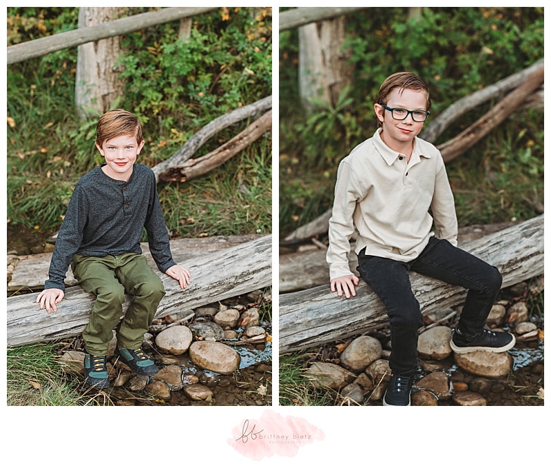 Boys sitting on a log in a creek