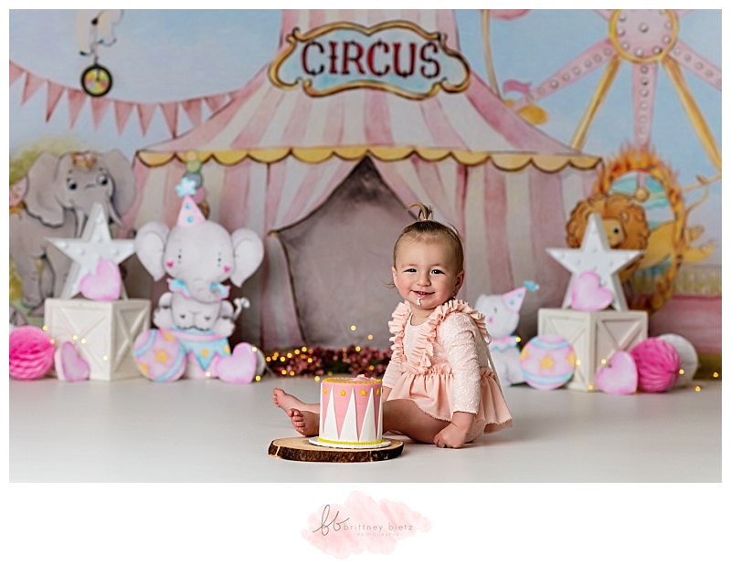 Baby girl smiling in front of her circus-themed cake smash in Calgary
