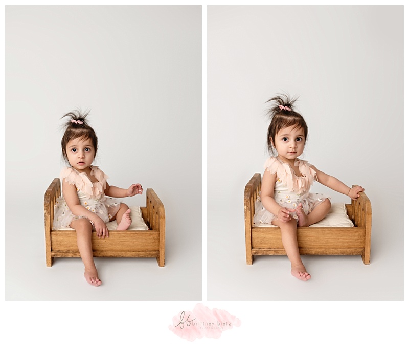 One-year old baby girl sitting on a bed before her cake smash photography session in Calgary