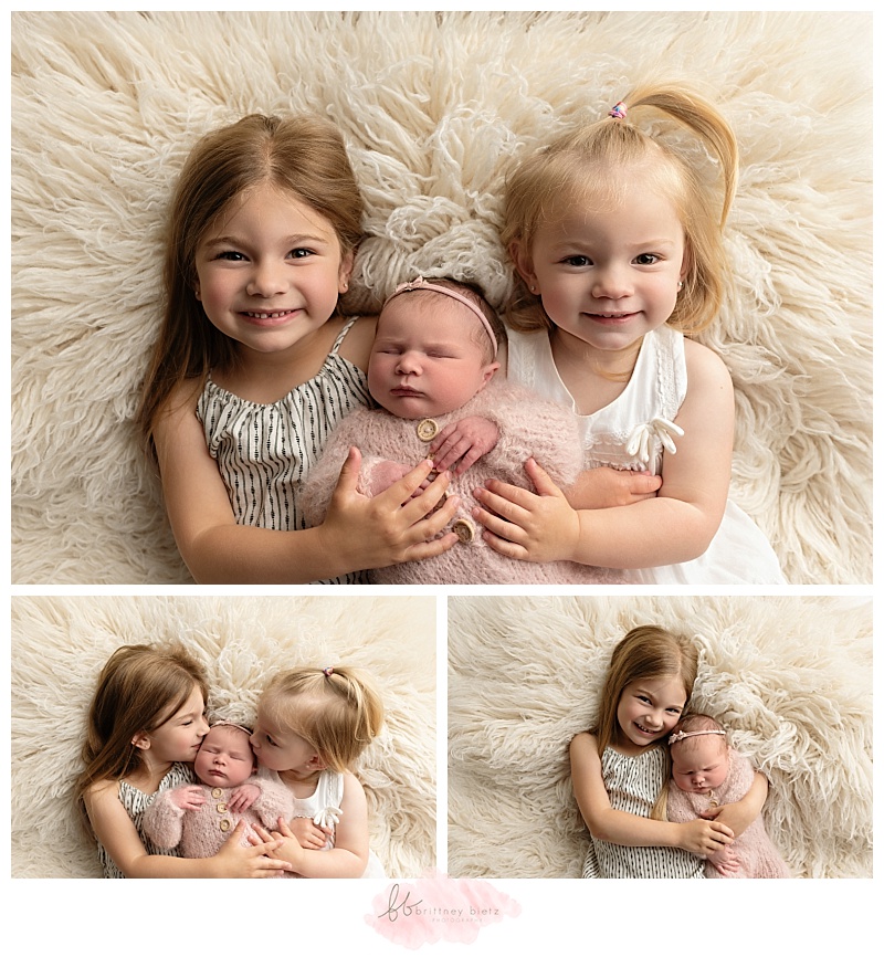 2 older sisters snuggling their newborn baby sister in Calgary