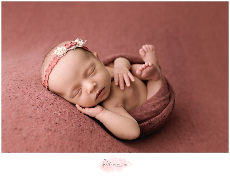 Calgary Newborn Photographer laying on back wrapped in raspberry