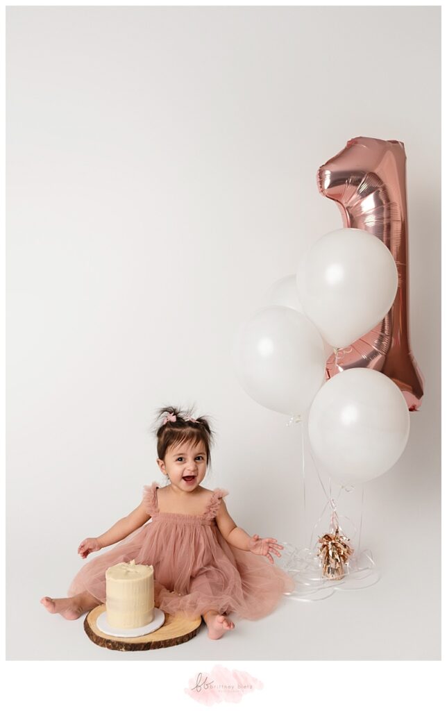 Cake-covered baby smiling and playing during a Cochrane cake smash session.