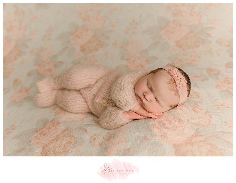 Cochrane newborn baby girl in side-laying pose on floral fabric