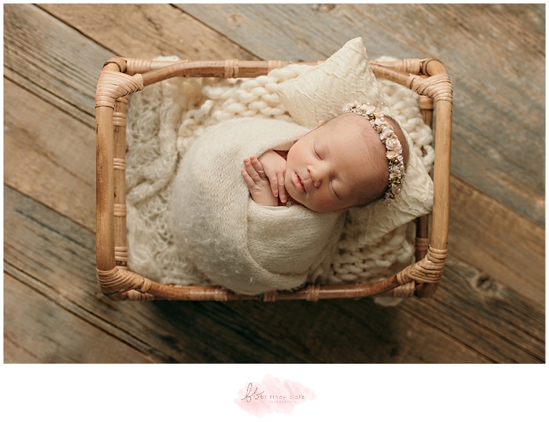 Wrapped baby girl in rustic bed with floral halo
