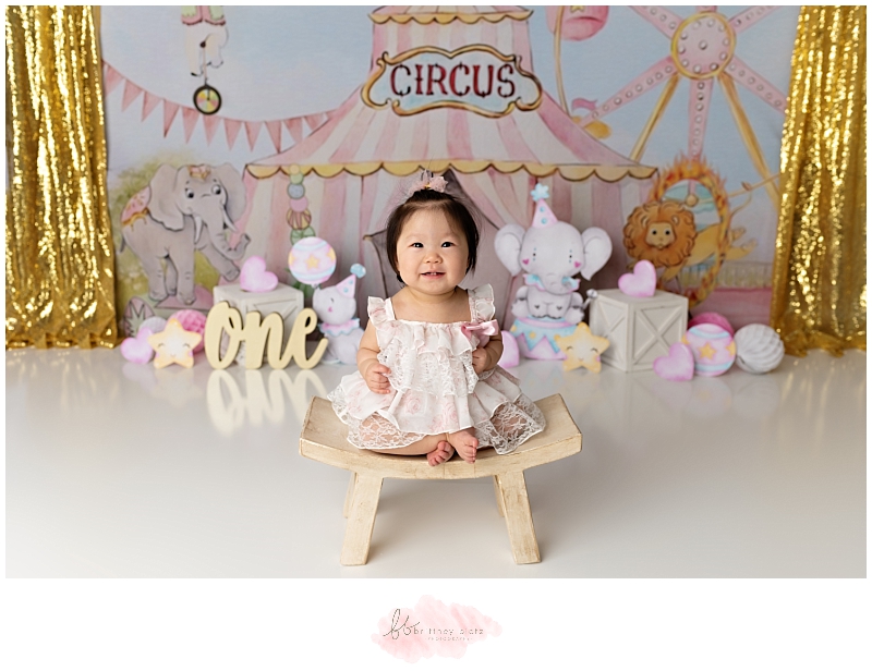 Girly circus themed cake smash with girl smiling and sitting on stool