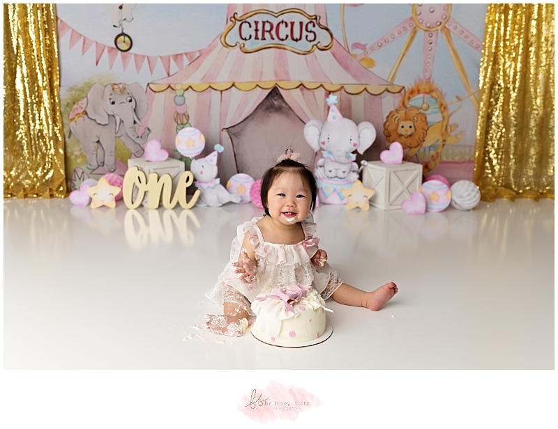 Girly circus themed cake smash with girl smiling and cake on face