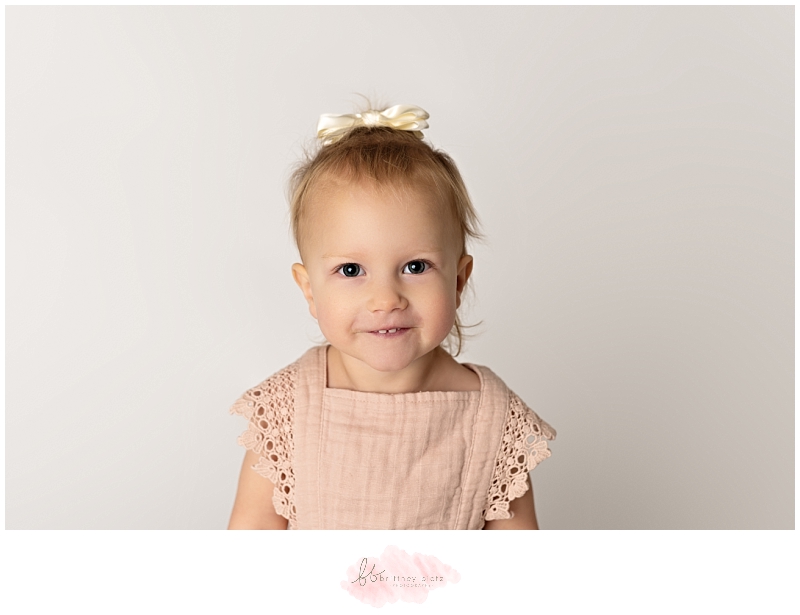 2-year old girl with bow in hair smiling at camera